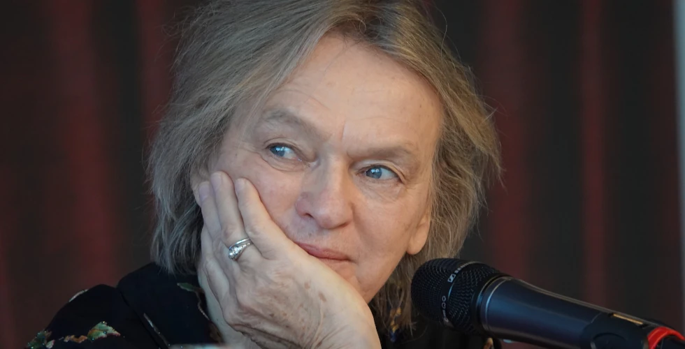 Elke Heidenreich vor dunkelrotem Hintergrund mit Mikrofon