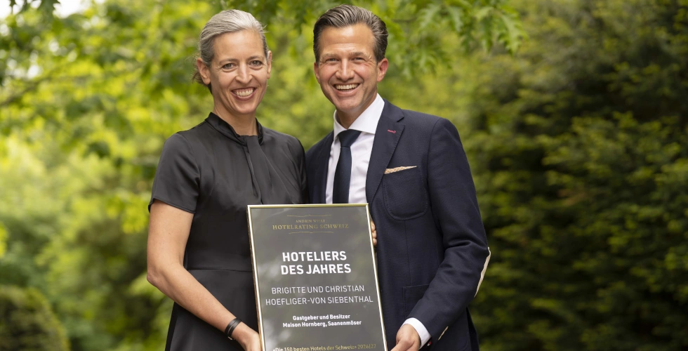 Hoteliers des Jahres - eine unfassbare Ehre für uns, das gesamte Team und Sie, unsere Gäste! 1 Zwei stolze Menschen stehen im Grünen und halten eine Tafel mit der Auszeichnung Hoteliers des Jahres in der Hand